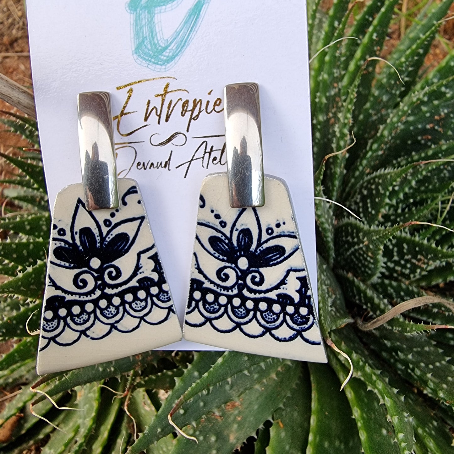 Aros de cerámica chilena, diseño azul y blanco en forma trapezoide.